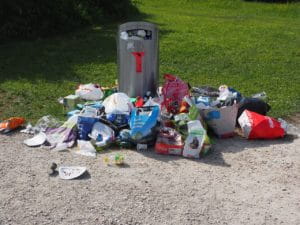 C'est une poubelle pleine, avec des déchets autour.