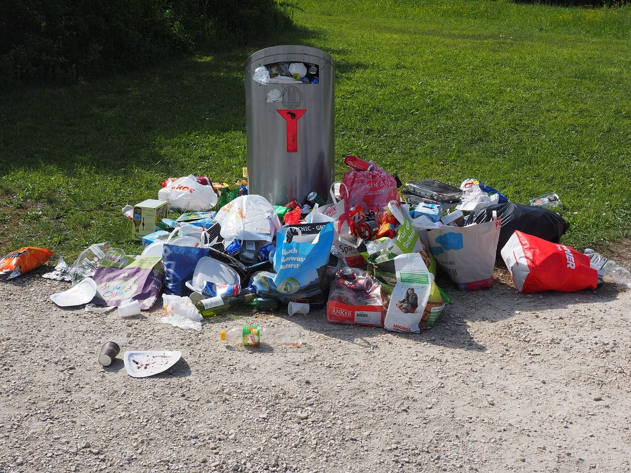 Une poubelle pleine, avec des déchets autour.